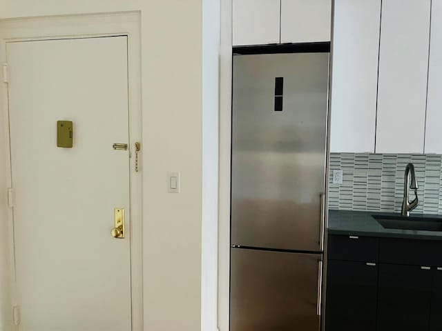 kitchen featuring sink, stainless steel built in refrigerator, tasteful backsplash, and white cabinetry