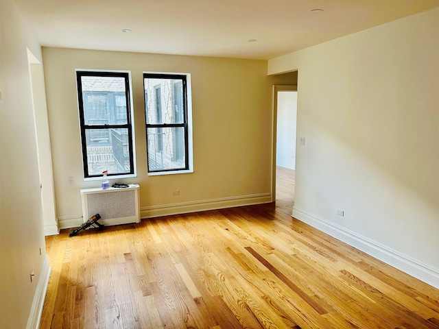 empty room with light wood-type flooring and radiator heating unit