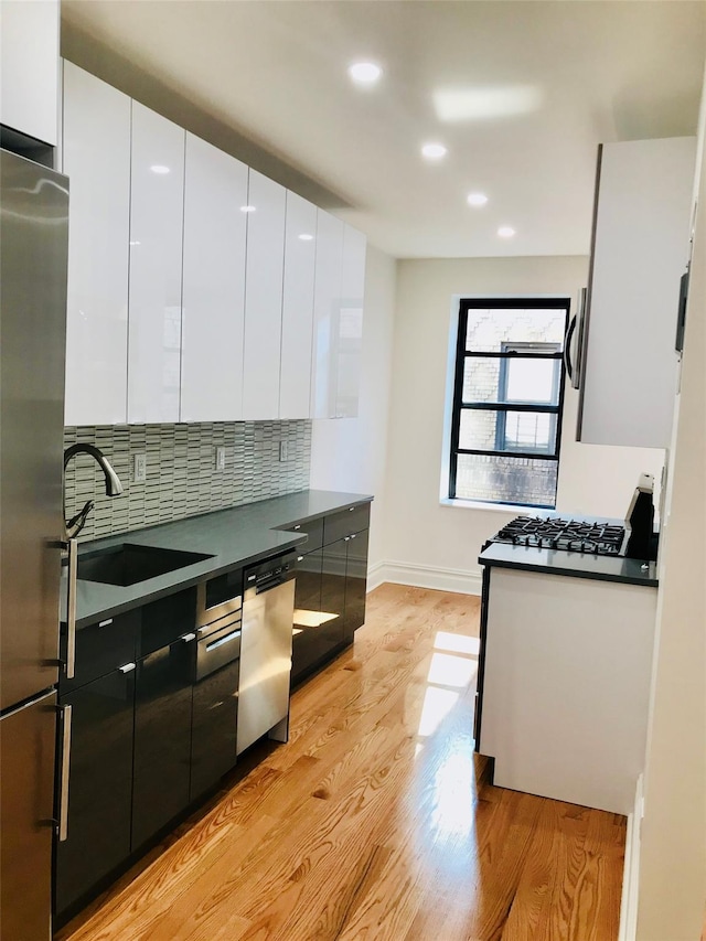 kitchen with white cabinets, appliances with stainless steel finishes, decorative backsplash, and sink