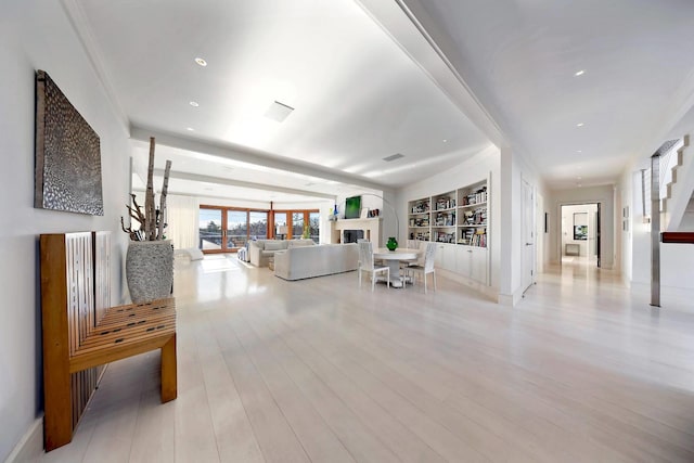 living room featuring crown molding, built in features, and light hardwood / wood-style floors