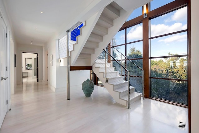 stairway with a wall of windows and hardwood / wood-style flooring