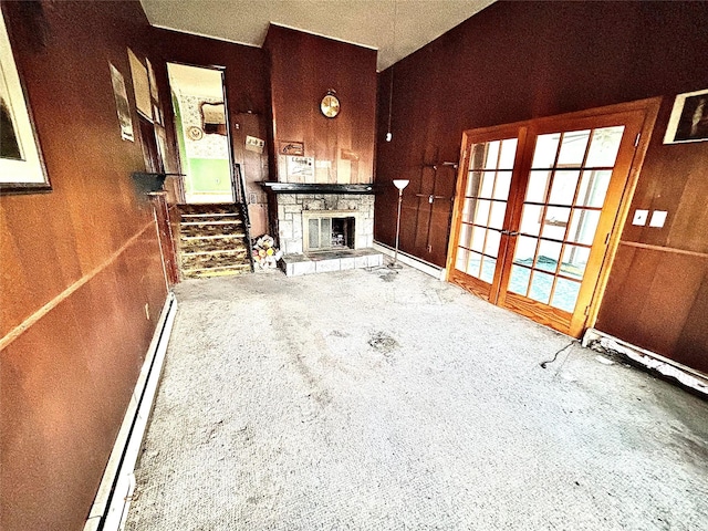 unfurnished living room featuring a baseboard heating unit, concrete flooring, a fireplace, and wood walls