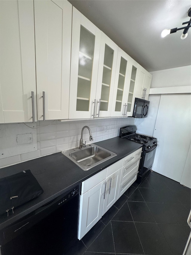 kitchen with tasteful backsplash, sink, white cabinets, dark tile patterned floors, and black appliances