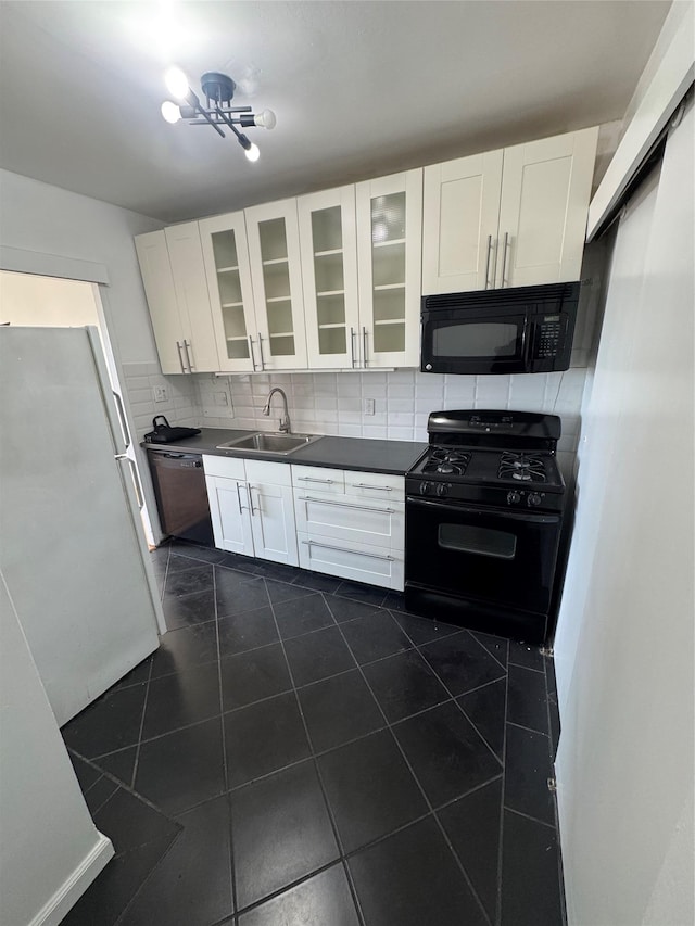 kitchen with sink, white cabinets, backsplash, dark tile patterned floors, and black appliances