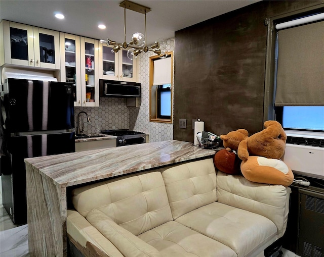 kitchen with black refrigerator, tasteful backsplash, stove, range hood, and sink