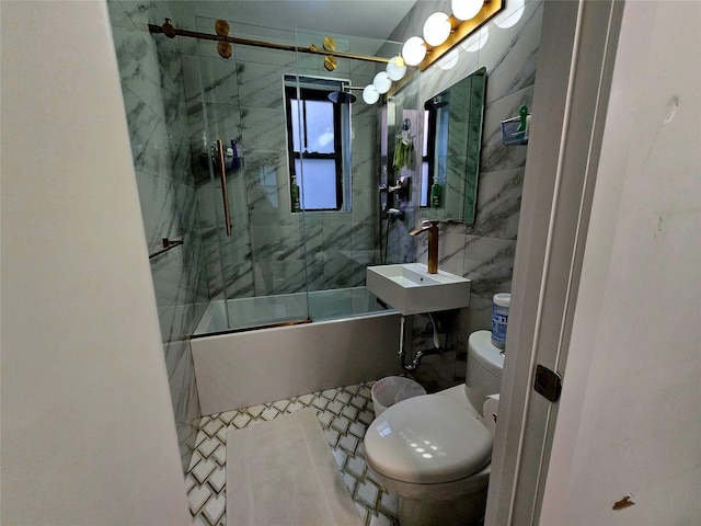 full bathroom featuring sink, tile walls, shower / bath combination with glass door, and toilet