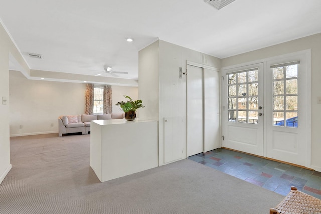 entrance foyer with french doors, ceiling fan, a healthy amount of sunlight, and light carpet