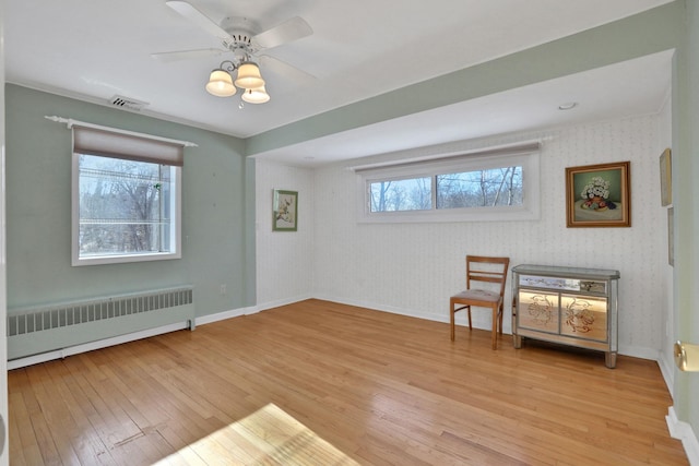 unfurnished room with radiator, ceiling fan, and light wood-type flooring