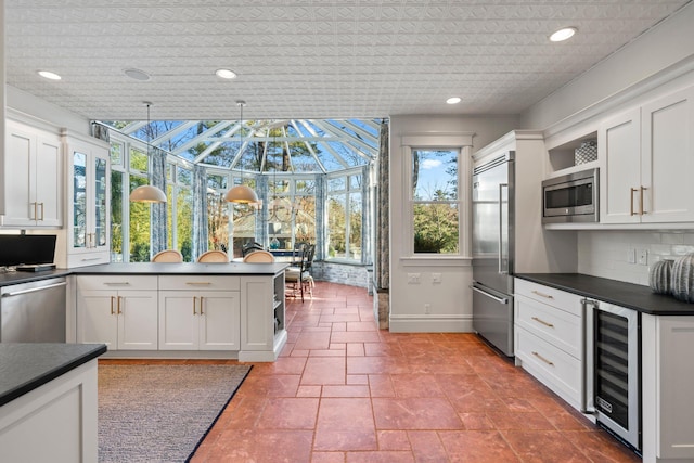 kitchen featuring decorative light fixtures, backsplash, built in appliances, white cabinetry, and beverage cooler