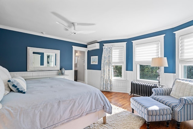 bedroom featuring hardwood / wood-style floors, a wall unit AC, ceiling fan, radiator, and crown molding