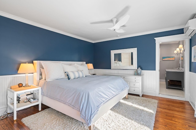 bedroom with an AC wall unit, ensuite bath, dark hardwood / wood-style flooring, ceiling fan, and crown molding