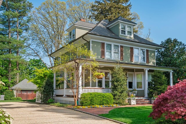 american foursquare style home with covered porch, a chimney, and fence
