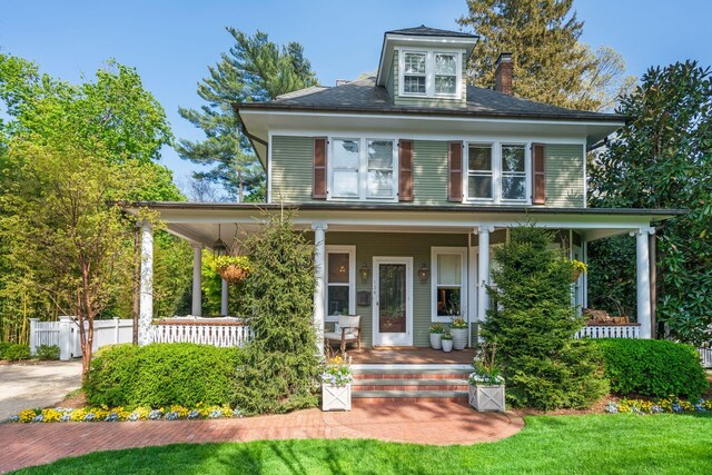 traditional style home with a porch, fence, and a chimney