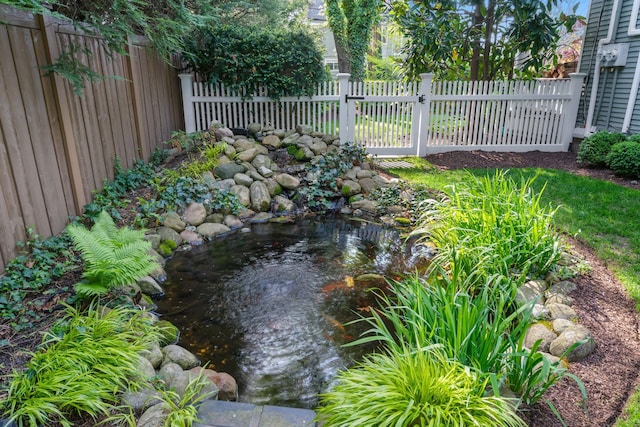 view of yard featuring a small pond and fence