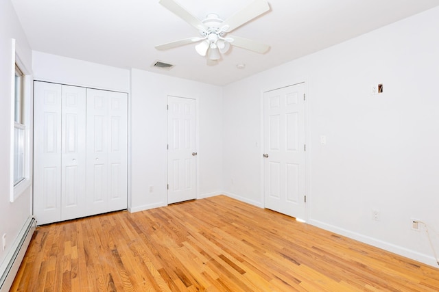 unfurnished bedroom with light wood-type flooring, ceiling fan, multiple closets, and a baseboard radiator