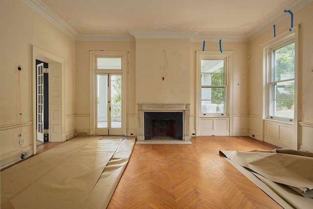 unfurnished living room featuring a wealth of natural light, light parquet floors, and ornamental molding