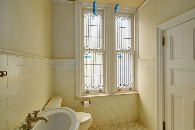 bathroom with sink, toilet, and tile walls