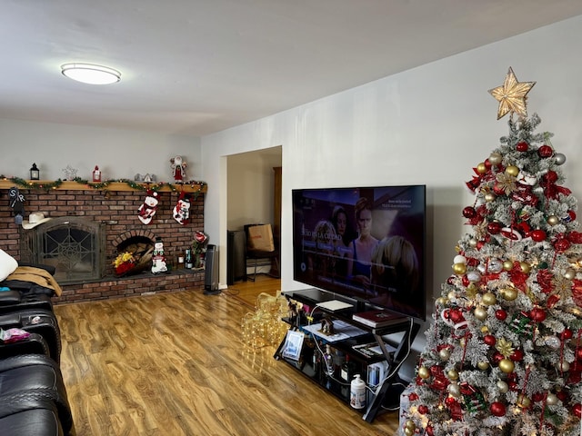 living room featuring wood-type flooring and a brick fireplace