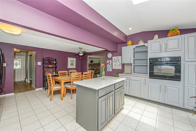 kitchen featuring ceiling fan, black oven, gray cabinetry, and a center island