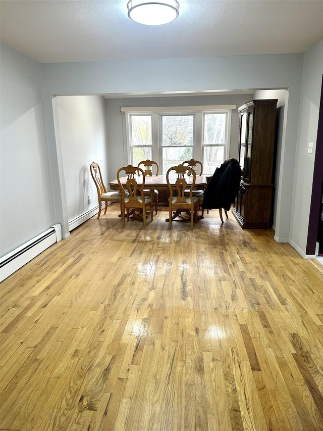 dining space with baseboard heating and light hardwood / wood-style floors