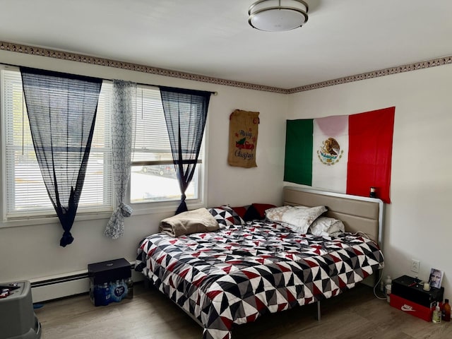 bedroom with baseboard heating and hardwood / wood-style floors