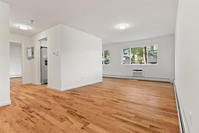 empty room featuring baseboard heating, light hardwood / wood-style floors, and an AC wall unit