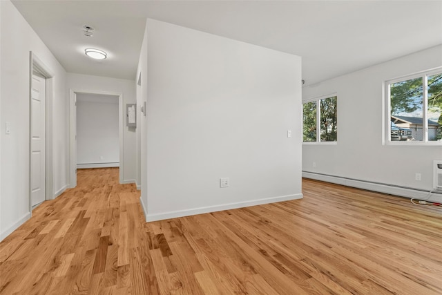 empty room with baseboard heating and light hardwood / wood-style floors