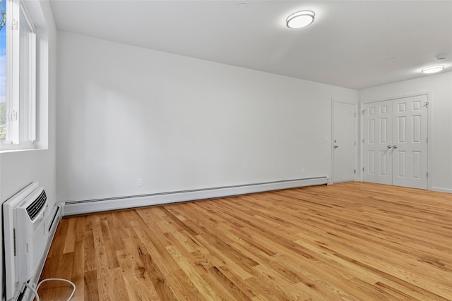 unfurnished room featuring baseboard heating and light hardwood / wood-style flooring