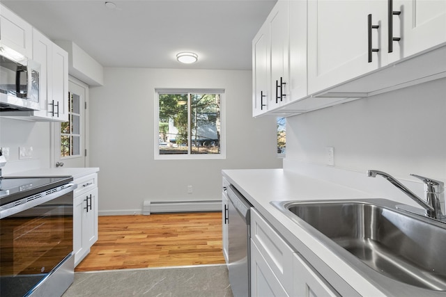 kitchen with a baseboard radiator, white cabinets, appliances with stainless steel finishes, sink, and light hardwood / wood-style flooring