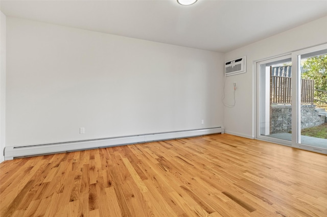 spare room featuring a wall unit AC, baseboard heating, and light hardwood / wood-style flooring