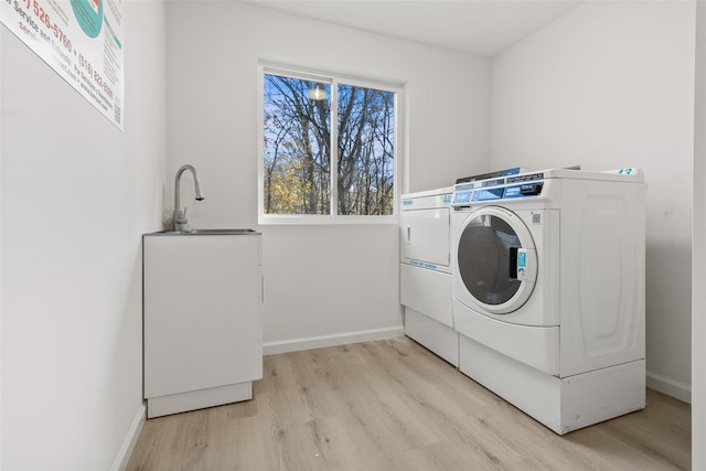 laundry room featuring sink, light hardwood / wood-style flooring, and independent washer and dryer