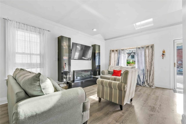 living room featuring crown molding, a healthy amount of sunlight, lofted ceiling with skylight, and hardwood / wood-style floors