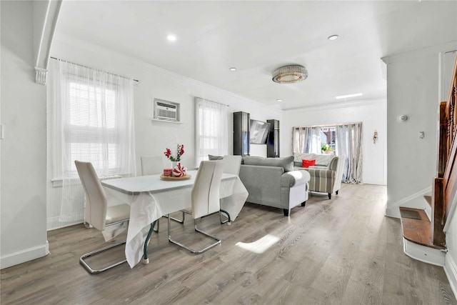 dining room with a healthy amount of sunlight, a wall unit AC, and light wood-type flooring