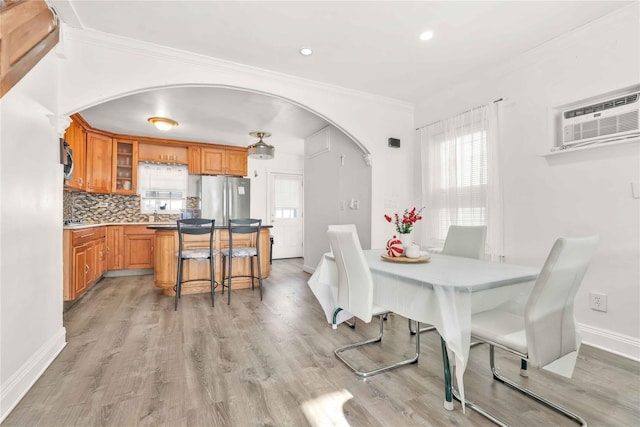 dining room featuring ornamental molding, a wall mounted air conditioner, and light hardwood / wood-style floors