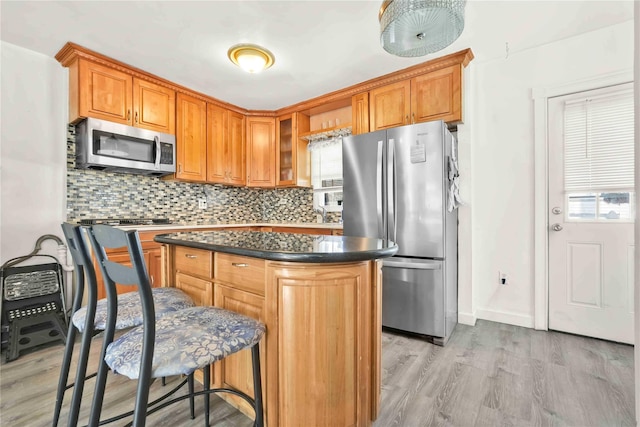 kitchen featuring backsplash, light wood-type flooring, stainless steel appliances, and a kitchen island