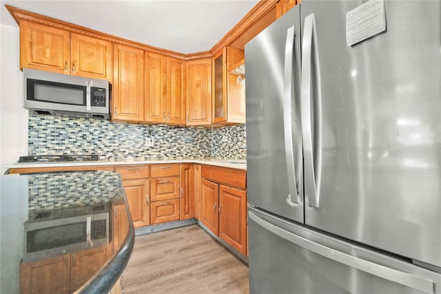 kitchen featuring tasteful backsplash, appliances with stainless steel finishes, and light hardwood / wood-style flooring