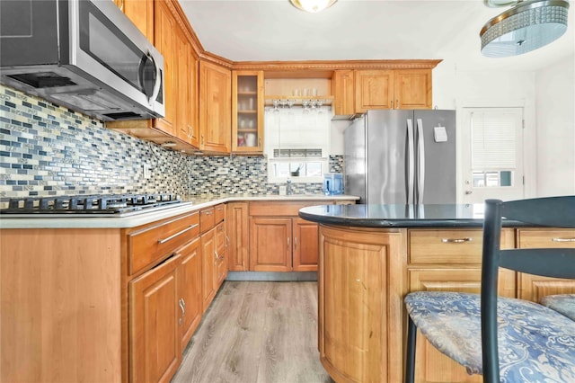 kitchen featuring tasteful backsplash, appliances with stainless steel finishes, sink, and light wood-type flooring