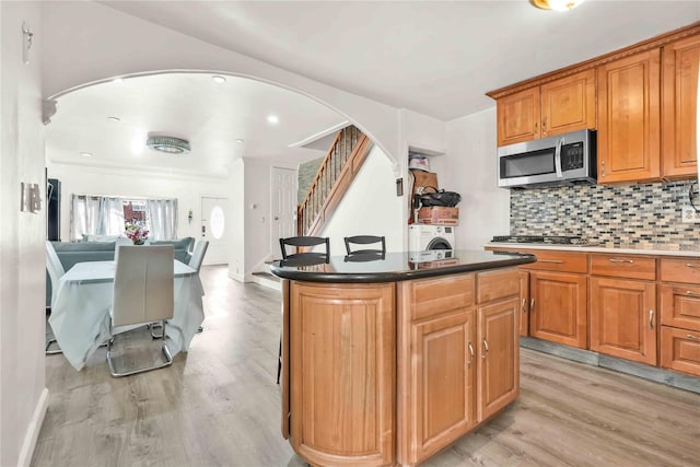 kitchen featuring a kitchen island, tasteful backsplash, appliances with stainless steel finishes, and light hardwood / wood-style floors