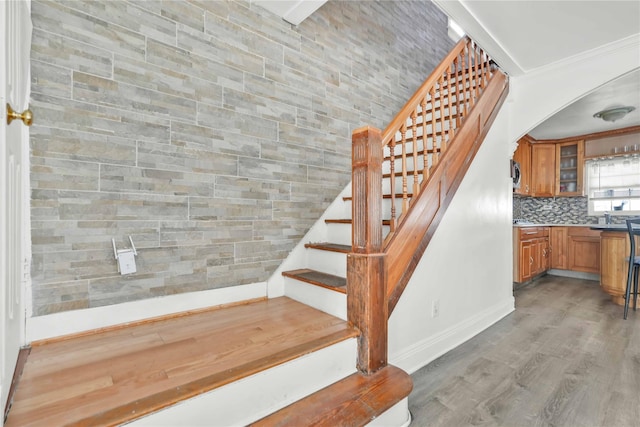 staircase featuring ornamental molding and wood-type flooring