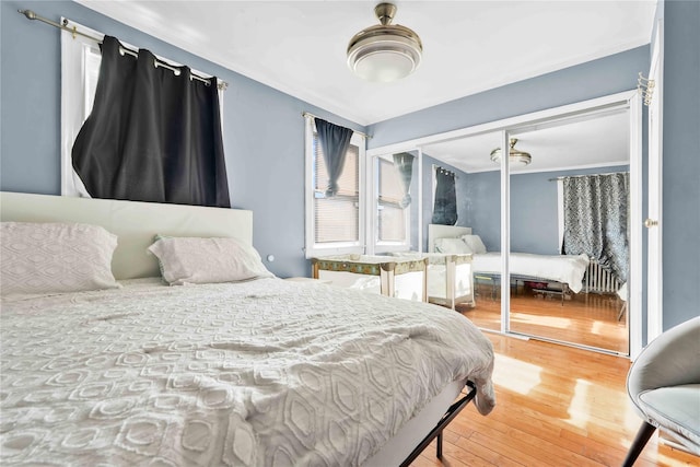 bedroom with wood-type flooring, radiator, and a closet