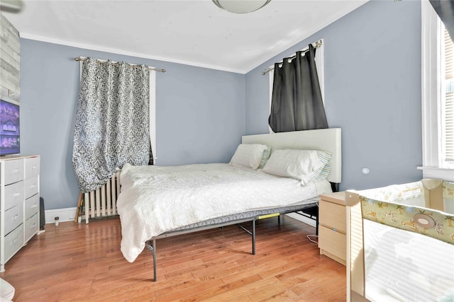 bedroom with hardwood / wood-style floors, ornamental molding, and radiator heating unit