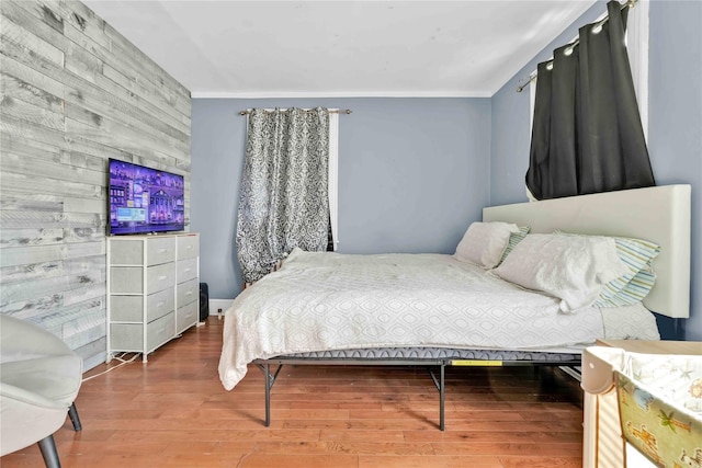 bedroom featuring wood-type flooring, ornamental molding, and wood walls