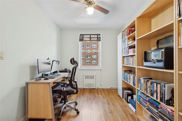 office space with radiator, ceiling fan, and light wood-type flooring