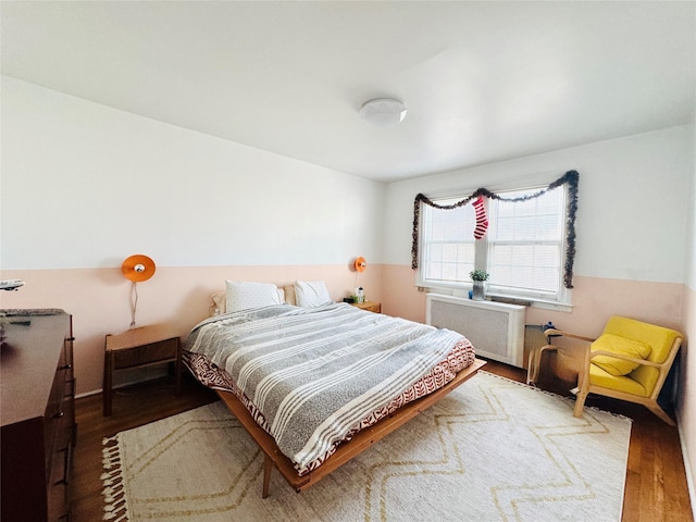 bedroom featuring radiator heating unit and hardwood / wood-style flooring