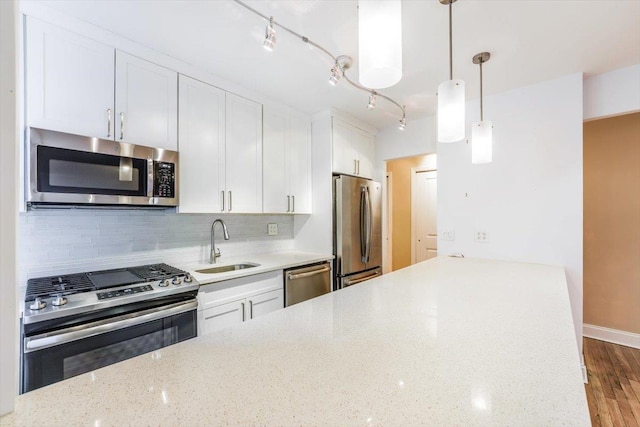 kitchen featuring appliances with stainless steel finishes, white cabinetry, decorative light fixtures, and decorative backsplash