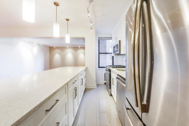 kitchen with stainless steel appliances, track lighting, hanging light fixtures, light stone counters, and white cabinetry