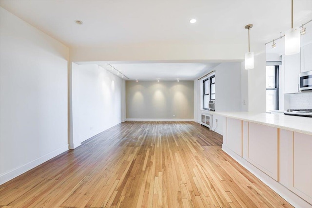 unfurnished living room with rail lighting, light hardwood / wood-style floors, and cooling unit