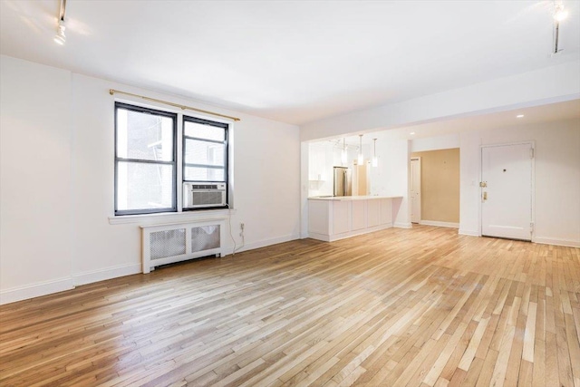 unfurnished living room with radiator, cooling unit, and light wood-type flooring