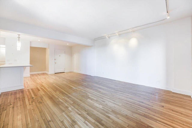 unfurnished living room featuring track lighting and light wood-type flooring