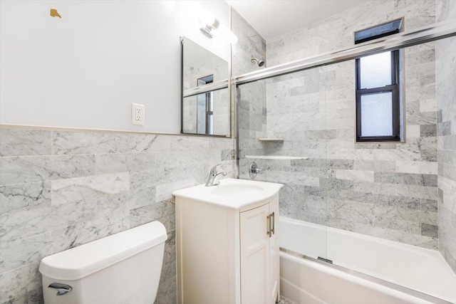 full bathroom featuring tile walls, enclosed tub / shower combo, vanity, and toilet